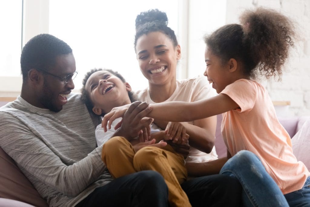 Overjoyed biracial family with kids have fun at home