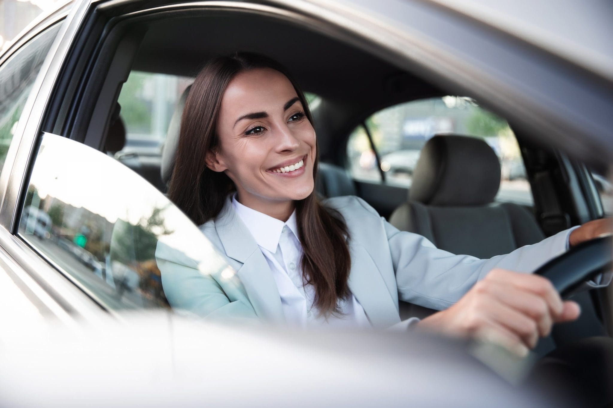 Beautiful happy successful businesswoman is driving a new modern